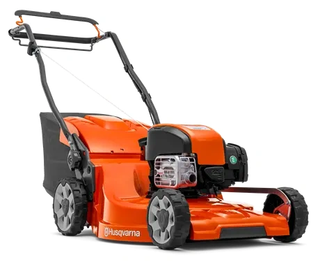 Kosiarka LC 253S Husqvarna w kolorze pomarańczowym z ciemnoszarymi akcentami, stojąca w lekkim zbliżeniu. Widoczne logo na obudowie, solidne koła oraz uchwyt do prowadzenia. Kosiarka z silnikiem spalinowym, przeznaczona do użytku ogrodowego.
