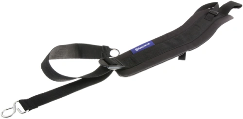 Czarny łącznik dmuchawy Husqvarna 150BT z trwałego materiału, przylegający do ciała. Produkt na stole, z boku, z metalowymi osłonami i logo Husqvarna na niebieskiej etykiecie. Zwiększa komfort pracy.