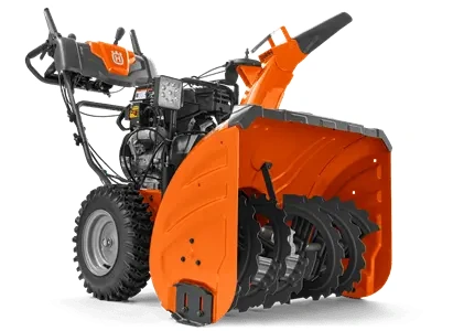 Odśnieżarka ST330 Husqvarna w kolorze pomarańczowym, ustawiona w pozycji stojącej; widok z boku ukazujący wirnik śrubowy oraz silnik. Ręczne uchwyty do prowadzenia, duże gumowe koła, na obudowie wyraźne logo Husqvarna. Tło neutralne.