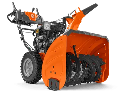 Odśnieżarka ST330 Husqvarna w kolorze pomarańczowym, ustawiona w pozycji stojącej; widok z boku ukazujący wirnik śrubowy oraz silnik. Ręczne uchwyty do prowadzenia, duże gumowe koła, na obudowie wyraźne logo Husqvarna. Tło neutralne.