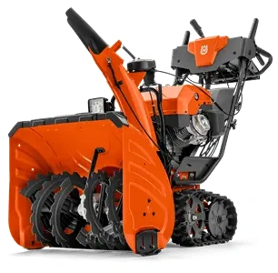 Odśnieżarka ST 427T Husqvarna w kolorze pomarańczowym z czarnymi detalami, z szeroką, zębatą strugą odśnieżającą oraz kółkami z bieżnikiem. Produkt stoi na podłożu, widok z boku. Na uchwycie znajdują się przyciski sterujące.