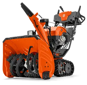 Odśnieżarka ST 427T Husqvarna w kolorze pomarańczowym z czarnymi detalami, z szeroką, zębatą strugą odśnieżającą oraz kółkami z bieżnikiem. Produkt stoi na podłożu, widok z boku. Na uchwycie znajdują się przyciski sterujące.