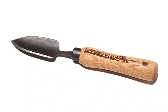 Łopatka do sadzenia bonsai Krumpholz z metalowym ostrzem i drewnianą rączką. Produkt widoczny z boku, z dużym ostrzem o lekko wyprofilowanym kształcie. Rączka naturalnego drewna z widocznym logo, ergonomiczny uchwyt.