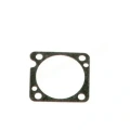 Uszczelka gaźnika do pilarek Husqvarna 555, 560XP/XPG, 562XP/XPG. Czarno-beżowa, kwadratowa o wycięciu na otwór wewnętrzny. Z widocznymi otworami montażowymi w rogach, płaska struktura. Produkt leży na jasnym tle.