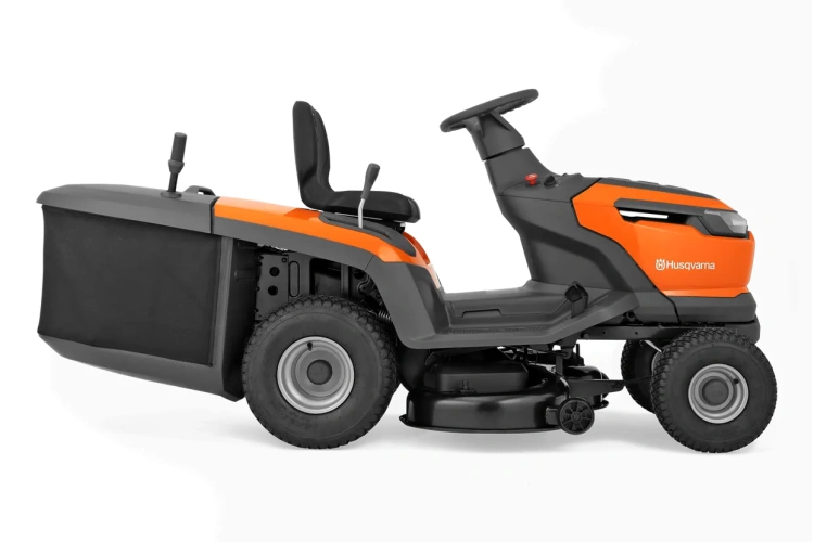 Traktor TC110i Husqvarna w kolorze pomarańczowym z szarymi akcentami, widoczny z boku. Posiada stół roboczy, duże koła oraz regulowane siedzisko. Widoczne logo Husqvarna na tylnej części. Produkt przystosowany do użytku w ogrodzie.