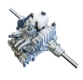 Przekładnia ridera R418Ts Husqvarna, metalowa, o srebrzystym wykończeniu, ukazuje widok z boku. Zawiera elementy mocujące oraz zbiornik na płyn. Widoczny wałek przesunięcia z obu stron. Produkt leży na jasnym tle, co podkreśla jego detale.