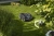 Robot koszący Husqvarna Automower® 405XE NERA w czarnej matowej obudowie na trawie, widoczny z boku z przyciskiem i kółkami. Obok piłka nożna, w tle skateboard i zieleń w naturalnym świetle.