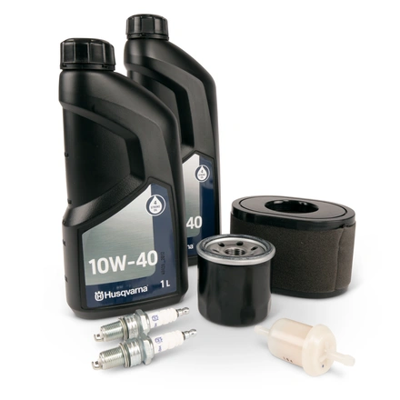 Zestaw serwisowy Husqvarna TC 220T zawiera dwa czarne opakowania oleju 10W-40, filtr oleju, filtr powietrza oraz świece zapłonowe. Elementy ułożone na białym tle, widoczne detale i tekstura opakowań.