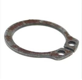 Pierścień zaciskowy do kosiarki WB 53S Husqvarna, okrągły metalowy element w kolorze ciemnoszarym z rdzą, z dwoma otworami montażowymi. Ujęcie z boku, ukazujące szczegóły kształtu i faktury powierzchni.