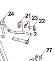 Fragment w kształcie litery L z metalowego materiału, z wyraźnymi otworami montażowymi, stanowiący element mechaniczny, widoczny w układzie z innymi komponentami. Ujęcie z boku, na białym tle.
