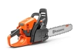 Pilarka Husqvarna 450S w pomarańczowo-czarnym kolorze, z łańcuchem, prowadnicą, ergonomiczną rączką oraz oznaczeniami bezpieczeństwa i logo. Zdjęcie z boku, produkt stojący.