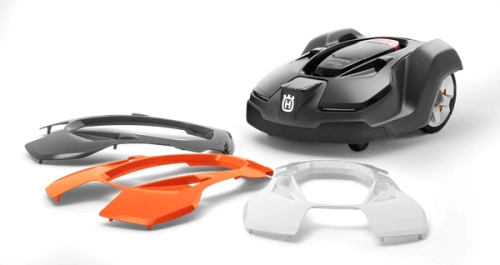 Biała obudowa 450xh do robota koszącego Husqvarna AUTOMOWER 450X, widok z góry. Obok robot i dwa elementy: pomarańczowy i czarny. Plastik, gładka powierzchnia, napis Husqvarna. Na czarnym tle.