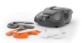 Obudowa robota koszącego Husqvarna AUTOMOWER 315X w kolorze szarym z wymiennymi osłonami w białym i pomarańczowym kolorze. Produkt widoczny z góry, złożony obok. Elementy są gładkie, z logo Husqvarna na głównym korpusie.