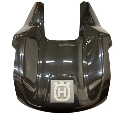 Pokrywa robota koszącego Automower Aspire R4 Husqvarna, ciemnoszara plastikowa, z opływowym przodem i metalowym logo Husqvarna. Leży na płaskiej, błyszczącej powierzchni.