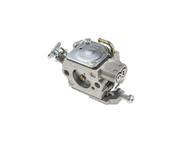 Gaźnik do piły Husqvarna 338 XPT/334 T, metalowy, o prostokątnym kształcie, z widocznym mocowaniem, sprężyną i wylotami. Ujęcie pod kątem, pokazujące górną część gaźnika oraz szczegóły montażowe. Brak logo.