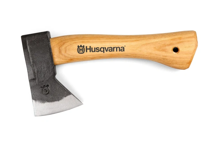 Toporek HUSQVARNA z metalowym ostrzem i drewnianą rączką, ukazana z boku. Ostrze ma ciemny, matowy kolor, a rączka jasną, chropowatą fakturę. Na rączce widoczne logo Husqvarna.