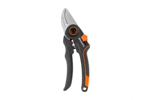 Sekator Husqvarna z ergonomicznym czarno-pomarańczowym uchwytem, ostrzem ze stali i widocznym mechanizmem sprężynowym po boku. Przedmiot jest na białym tle w pionowej pozycji.
