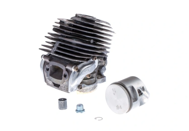 Cylinder kompletny pilarki Husqvarna 560XP/562XP, szary, o metalowej fakturze. Widok z boku, ukazujący detale komory spalania i aluminiowe żebra chłodzące. Element z mocowaniami, przeznaczony do montażu w pilarkach.