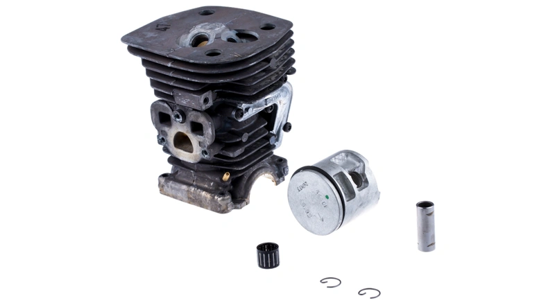 Cylinder pilarki Husqvarna 455 e-series Rancher II z metalowym korpusem w odcieniu szaro-srebrnym. W komplecie tłok, pierścienie oraz niewielki element mocujący. Produkt leży płasko na białym tle, ukazując detale konstrukcji.