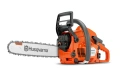 Pilarka Husqvarna 543XP z pomarańczową obudową, metalowym łańcuchem i prowadnicą, z ergonomiczną rączką i ostrogą. Produkt stoi na tle, ukazując detale mechanizmu i mocowania.
