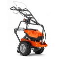 Układarka akumulatorowa przewodu instalacyjnego CL 400i Husqvarna, pomarańczowo-czarny, z dużą teksturowaną rączką i dwoma szarymi kołami. Nowoczesny, prosty design do układania przewodu instalacyjnego.