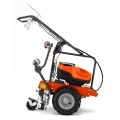 Układarka akumulatorowa przewodu instalacyjnego CL400i Husqvarna, boczny widok. Ergonomiczna rączka, pomarańczowy korpus, czarne detale, stabilne koła na jednolitym tle.