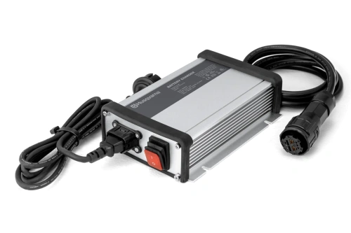 Ładowarka PS300C Husqvarna, czarna, prostokątna, z logo na obudowie. Wtyczka z kablami do ładowania. Ustawiona poziomo na jednolitym tle, idealna do ładowania kosiarek samojezdnych.