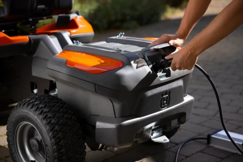 Ładowarka PS300C Husqvarna, w trakcie użytkowania, widoczne gniazdo ridera akumulatorowego z podłączoną ładowarką ridera.