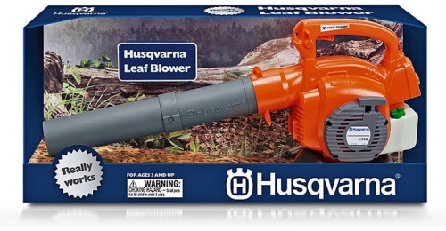 Dmuchawa do liści Husqvarna - pomarańczowa zabawka dziecięca z szarym wylotem. Opakowanie niebieskie z grafiką lasu, napis „Husqvarna Leaf Blower” i ostrzeżeniem bezpieczeństwa, widok frontalny.