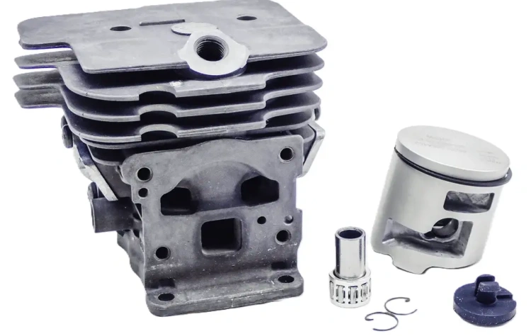 Cylinder pilarki T540 XP II w kolorze szarym, z metalowym tłokiem. Z przodu widoczne otwory montażowe. W komplecie mały zawór, tulejka i pierścień. Elementy ułożone na białym tle. Cylinder pokazany w pozycji leżącej, w zbliżeniu na detale.
