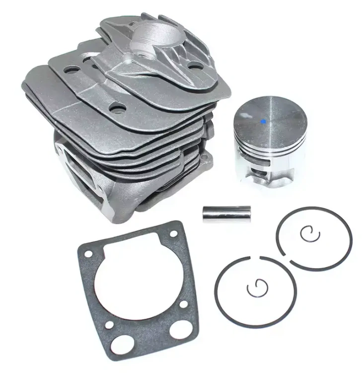 Cylinder kompletny pilarki 570 Husqvarna z metalowym korpusem w odcieniu szaro-srebrnym i sześcioma żeberkami chłodzącymi. W komplecie tłok, pierścienie oraz niewielki element mocujący. Produkt leży płasko na białym tle, ukazując detale konstrukcji.