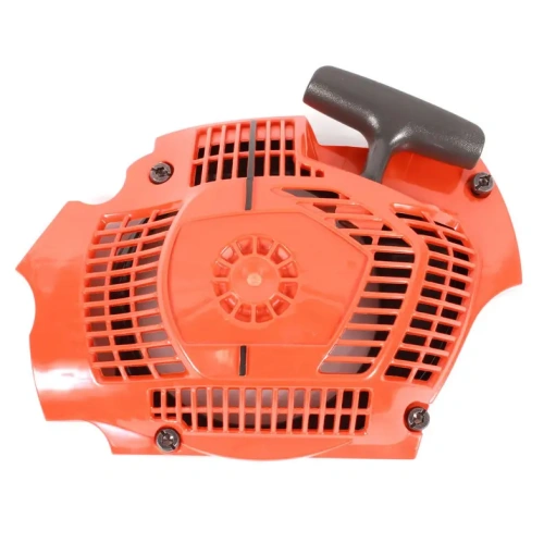 Pokrywa rozrusznika pilarki Husqvarna 570 koloru pomarańczowego, wykonana z tworzywa sztucznego. Widoczne otwory wentylacyjne po bokach, element montażowy z prawej strony. Brak widocznego logo, widok z góry.