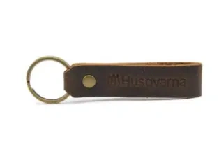 Brelok skórzany z logo Husqvarna, długość ok. 8 cm, z pierścieniem do zawieszenia, na jasnym tle, widok frontalny.