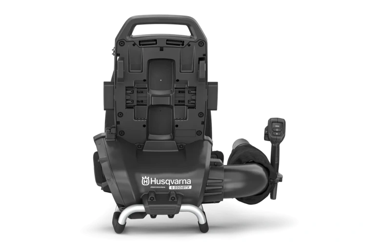 Dmuchawa akumulatorowa 550iTBX w kolorze pomarańczowym i czarnym, w układzie stojącym, z widoczną rękojeścią i wylotem powietrza. Produkt ma ergonomiczny kształt, logo Husqvarna na obudowie oraz przewód do ładowania. Tło jest jednolite.