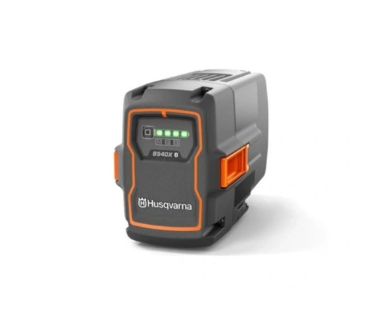 Akumulator Husqvarna 40-B540X w kolorze czarnym z pomarańczowymi akcentami, z widocznym wskaźnikiem naładowania i logo. Ujęcie frontalne, produkt stojący na płaskiej powierzchni, z wyraźnymi detalami konstrukcyjnymi.