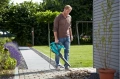 Praca przy użyciu dmuchawa-odkurzacz elektryczna Gardena Ergojet 3000, w kolorze niebieskim z elementami szarymi, z długą rurą powietrzną.