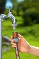 Szybkozłącze 19 mm 3/4" Gardena, z widocznymi uchwytami do łatwego montażu. Ujęcie frontalne, produkt stoi na jednolitym tle. Wysoka jakość materiału, Widoczne przy użyciu razem z wężem.
