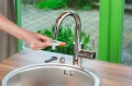 Adapter do kranów wewnętrznych Gardena, pokazany sposób mocowania na kranie kuchennym, zdjęcie podczas użytkowania.