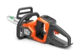 Pilarka akumulatorowa Husqvarna 215i w kolorze pomarańczowym z szarymi elementami, w ujęciu bocznym. Widoczna łańcuchowa układanka z logo Husqvarna, ergonomiczny uchwyt oraz przycisk uruchomienia. Produkt leży na jasnym tle.