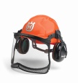 Kask leśny Classic Husqvarna w intensywnym pomarańczowym kolorze, z siatką ochronną z przodu i czarnymi nausznikami. Produkt jest ustawiony w lekkim zbliżeniu z boku, ukazując detale mocowania oraz widoczny symbol Husqvarna na czapie. Tło białe.