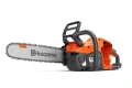 Pilarka akumulatorowa Husqvarna 440i w kolorze pomarańczowym z szarymi detalami, widoczna z boku. Posiada długi, metalowy łańcuch oraz ergonomiczny uchwyt. Na obudowie umieszczone logo Husqvarna. Produkt stoi na stabilnej powierzchni.