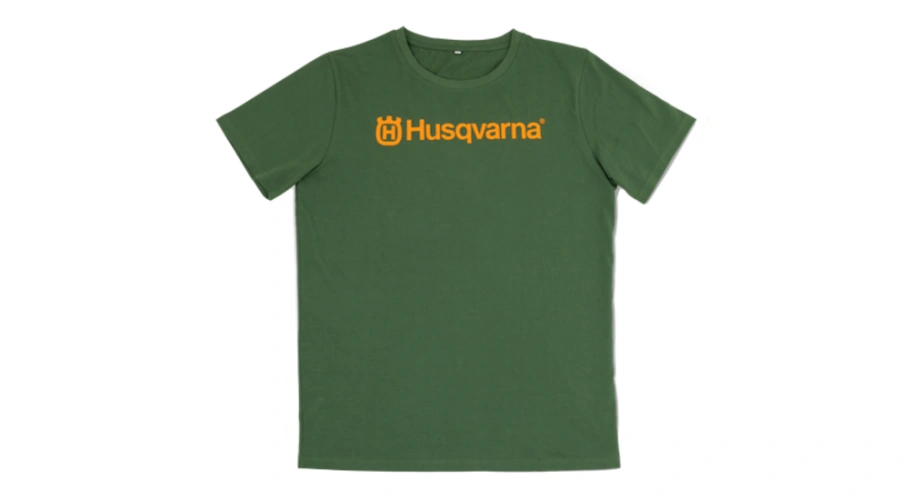 Zielony T-shirt z krótkim rękawem, prostym krojem. Na piersi znajduje się wyraźny napis Husqvarna w pomarańczowym kolorze. Produkt jest prezentowany frontalnie na jednolitym tle, z widocznymi detalami szwów i wykończeń.