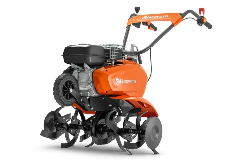 Kultywator TF 435P Husqvarna w kolorze pomarańczowym z czarnym silnikiem, z widocznymi metalowymi nożami. Ujęcie z boku, stojący, ukazujący detale konstrukcji i chwyt. Logo Husqvarna wyraźne na obudowie. Tło czarne, podkreślające produkt.