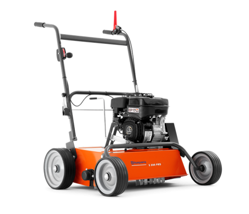 Wertykulator S500 PRO Husqvarna w kolorze pomarańczowym z metalową obudową, umieszczony na dwóch dużych, szerokich kołach. Silnik widoczny z boku, a na uchwycie znajdują się dźwignie. Produkt stoi na wprost, prezentując szczegóły konstrukcji.