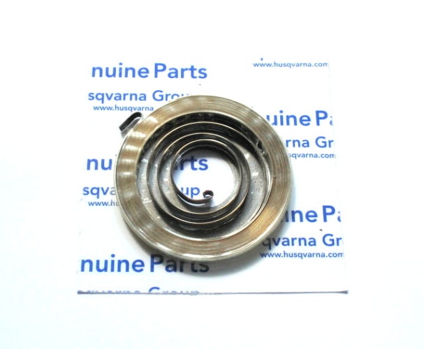 Sprężyna rozrusznika pilarki Partner P340S, metalowa, w kształcie sprężyny, na białym tle z niebieskimi napisami genuine Parts. Zbliżenie na kilka okręgów o równomiernej szerokości, jeden z końców przytwierdzony do podstawy.