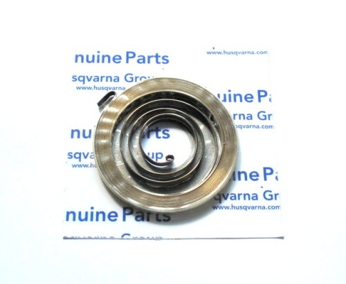 Sprężyna rozrusznika pilarki Partner P340S, metalowa, w kształcie sprężyny, na białym tle z niebieskimi napisami genuine Parts. Zbliżenie na kilka okręgów o równomiernej szerokości, jeden z końców przytwierdzony do podstawy.